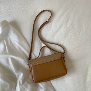 Close-up of brown leather handbag with woven texture detail and adjustable strap