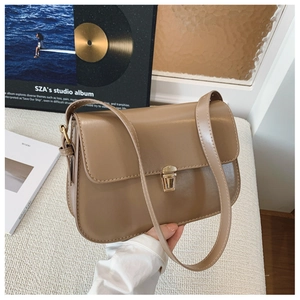 Detail of khaki faux leather shoulder bag with gold metal clasp and adjustable strap