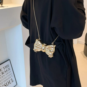 Golden bow-shaped hard shell clutch bag with metallic texture and sleek chain strap