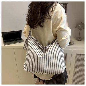 Detail of minimalist black and white striped canvas tote bag worn by a model in lifestyle setting