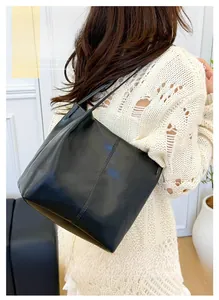 Detail of minimalist black leather tote bag featuring sleek vertical stitching and slim straps