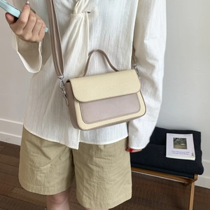 Detail of beige contrast handbag with woven flap and adjustable strap on a model