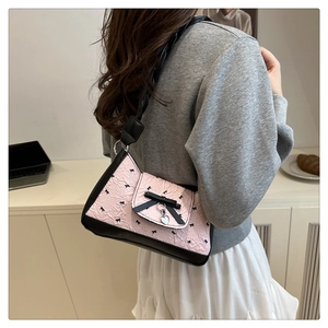 Détail du sac plissé rose avec motifs nœuds noirs et pendentif cœur argenté
