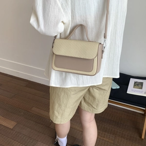 Detail of crossbody bag featuring woven texture flap and smooth leather in beige-brown tone