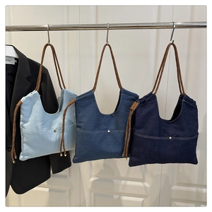 Detail view of denim tote bags in light, medium and dark blue with rope straps