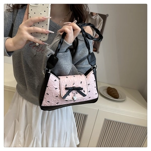 Sac à main rose plissé avec nœud noir et pendentif cœur, présenté en mode selfie