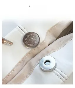 Close-up of the silver magnetic closure and stitching on the white leather tote bag