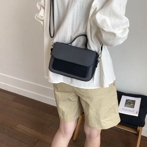 Detail of elegant black and grey textured shoulder bag worn with a white shirt