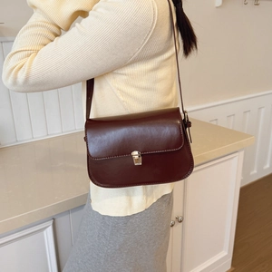 Vintage dark burgundy leather baguette bag with silver buckle worn on shoulder