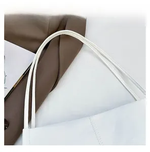 Detail of white leather tote bag featuring durable double straps and minimalist stitching