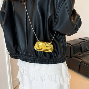 Elegant gold oval metallic crossbody bag with fine chain strap shown on model fashion look