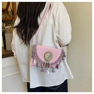 Dettaglio della borsa a tracolla intrecciata rosa con perline e nappe etniche