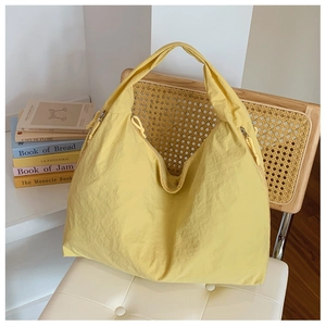 Détail d'un sac cabas en nylon jaune avec fermeture éclair latérale et tissu texturé