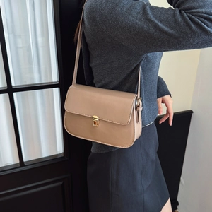 Minimalist beige baguette shoulder bag with gold metal buckle shown on model's shoulder