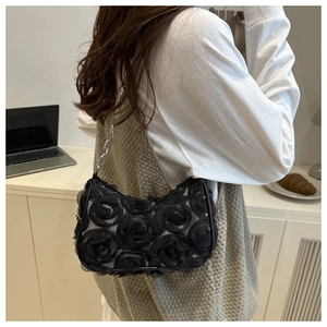 Detail of 3D fabric rose texture on black clutch with silver metal chain strap