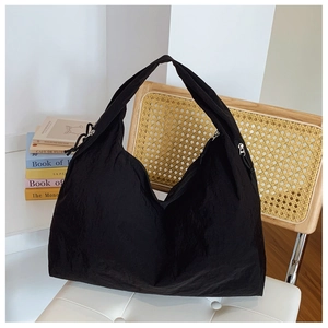 Détail d'un sac cabas noir en nylon avec larges anses et fermetures éclair argentées