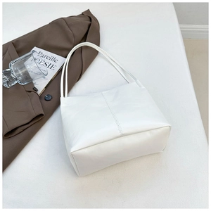 Minimalist white leather tote bag with vertical stitching shown in a lifestyle setting