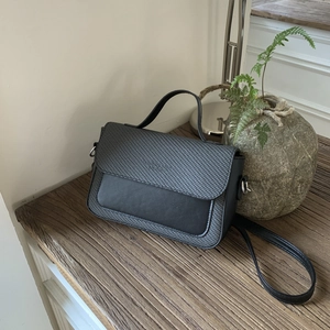 Detail of black crossbody bag featuring textured rhombus stitching and matte finish leather
