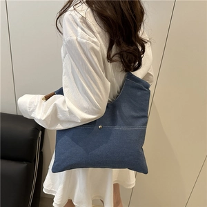 Minimalist blue denim shoulder bag with white stitching and decorative wooden handle