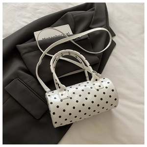 Vue détaillée de dessus d'un sac à main à pois crème posé sur un blazer gris texturé
