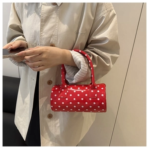 Détail d'un mini sac Boston rouge à pois blancs en cuir verni brillant et élégant