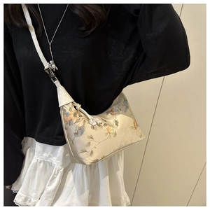 Detail of champagne satin crossbody bag with floral bird embroidery and pearl strap