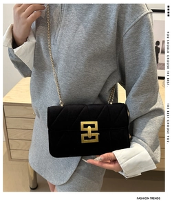 Detailed view of black velvet quilted crossbody bag featuring vintage gold geometric clasp