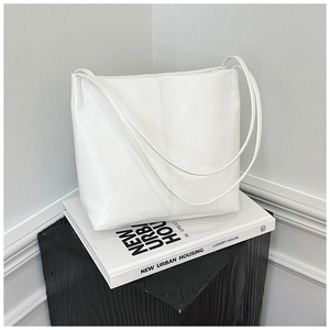 Detail of white PU leather tote bag with vertical stitching on minimalist books