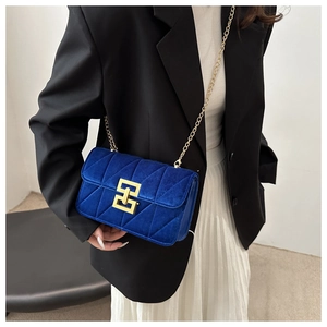 Detail of royal blue velvet quilted bag with a gold rectangular metal turn lock and chain