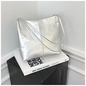 Detailed view of silver metallic leather tote bag with slim straps on minimal background