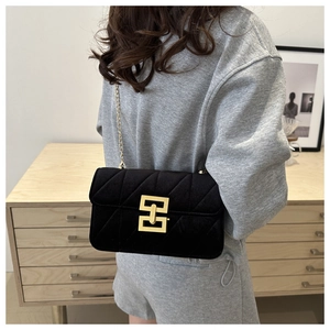 Detail of black velvet crossbody bag with quilted texture and gold square buckle