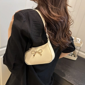 Chic beige shoulder bag with gold bow accent and pebble leather texture for women