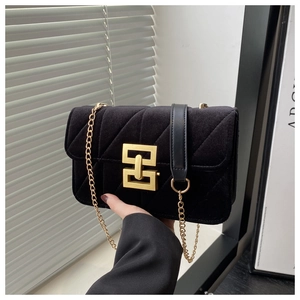 Detail view of black velvet handbag featuring golden V-quilted texture and metal lock