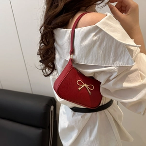 Chic red shoulder bag with golden bow accent and premium pebble grain texture