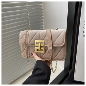 Detailed macro of the velvet quilted texture and gold lock on the beige crossbody bag