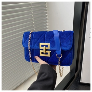 Detailed view of royal blue velvet shoulder bag with diamond quilting and gold lock