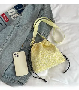 Vue détaillée du sac jaune texturé à fleurs en relief avec fermeture à cordon