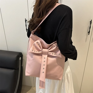 Pink bow tote bag with silver studs shown on shoulder for a stylish commuting look