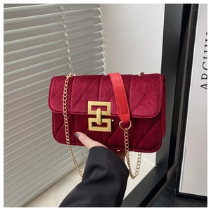 Detail of burgundy velvet quilted bag with golden geometric clasp and chain strap