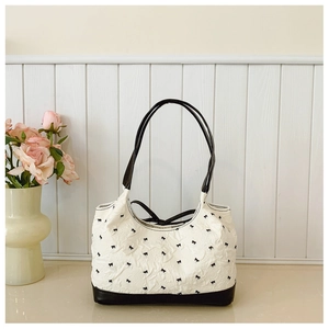 Detail of white textured fabric with bow pattern and contrast black leather strap
