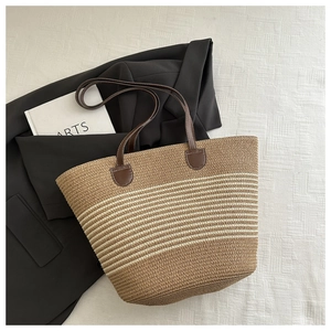 Detail of handwoven striped straw tote bag with brown faux leather handles for summer