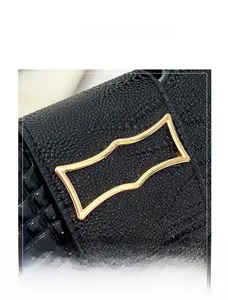 Detail of black crocodile texture leather bag with glossy gold metallic buckle
