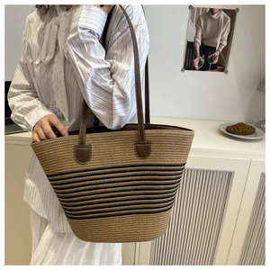 Detail of straw tote bag with black stripes and brown leather straps for summer