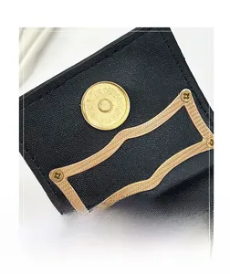 Close-up of golden magnetic closure with engraving on a black stone-textured crescent bag