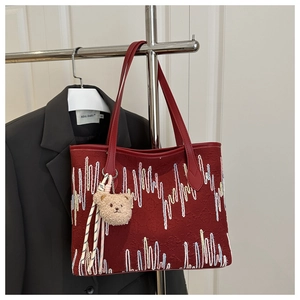 Détail du sac cabas rouge avec broderie colorée et pendentif ours en peluche