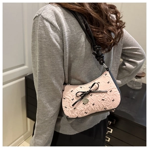 Close-up of pink bow bag with embossed texture and metal heart charm detail