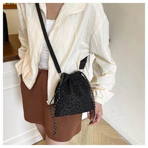 Détail du sac seau noir à cordon en jacquard floral avec bandoulière tissée réglable
