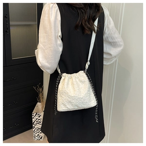 Détail du sac seau blanc à texture jacquard avec cordons de serrage noirs contrastés