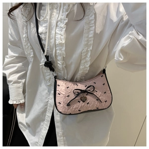 Détail du sac bandoulière plissé rose avec nœud noir et pendentif cœur argenté