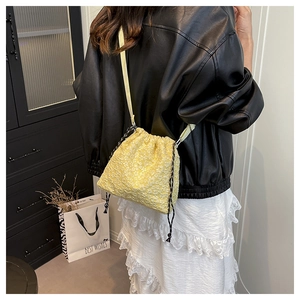 Détail du sac seau jaune à cordon avec texture popcorn et fine bandoulière